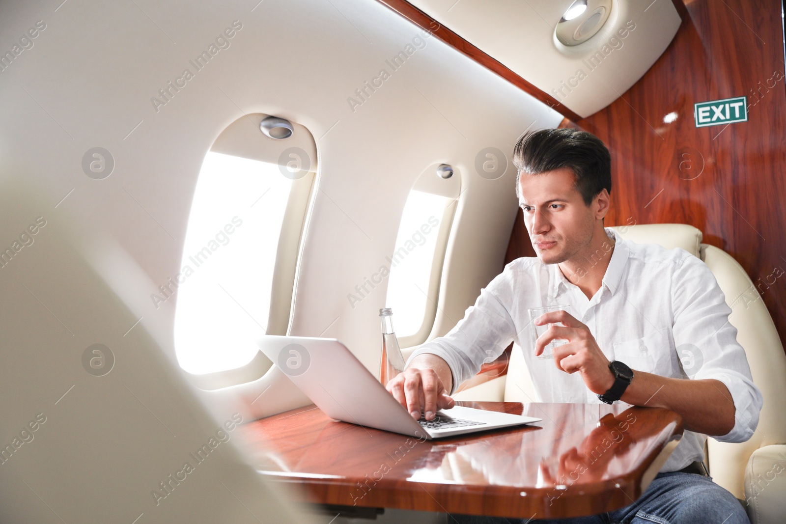 Image of Handsome man working with laptop on plane. Comfortable flight