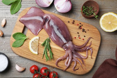 Photo of Flat lay composition with fresh raw squid and garnish ingredients on wooden table