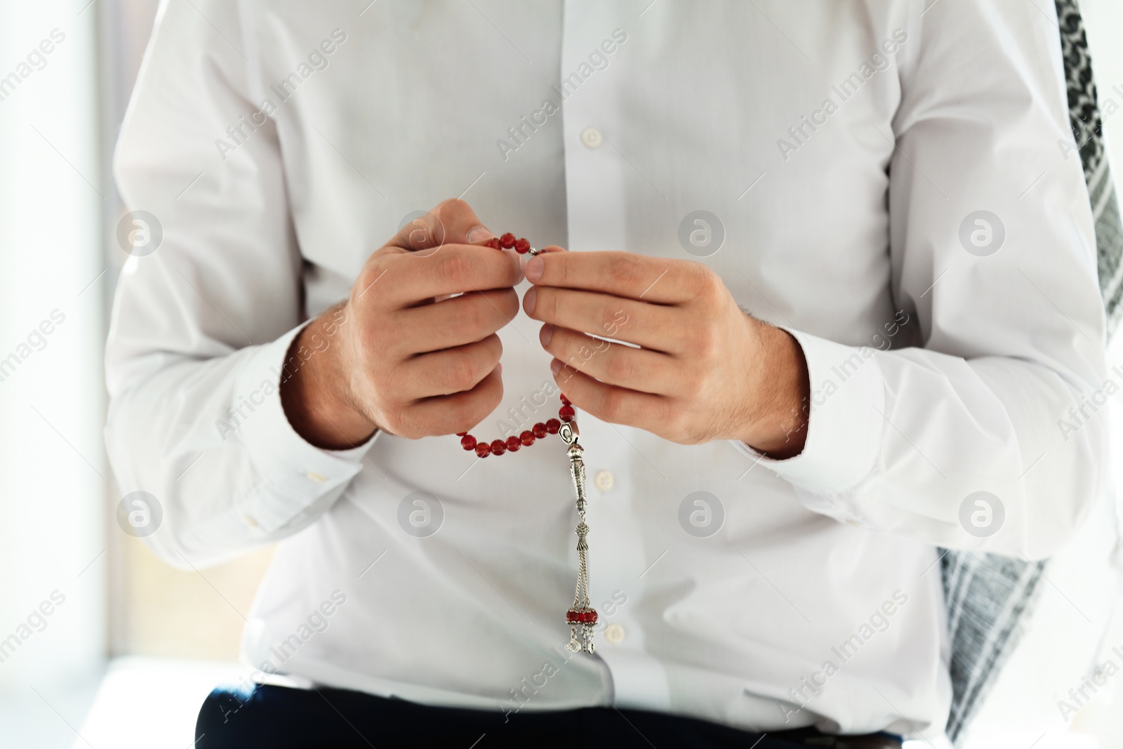 Photo of Muslim man with misbaha praying indoors, closeup