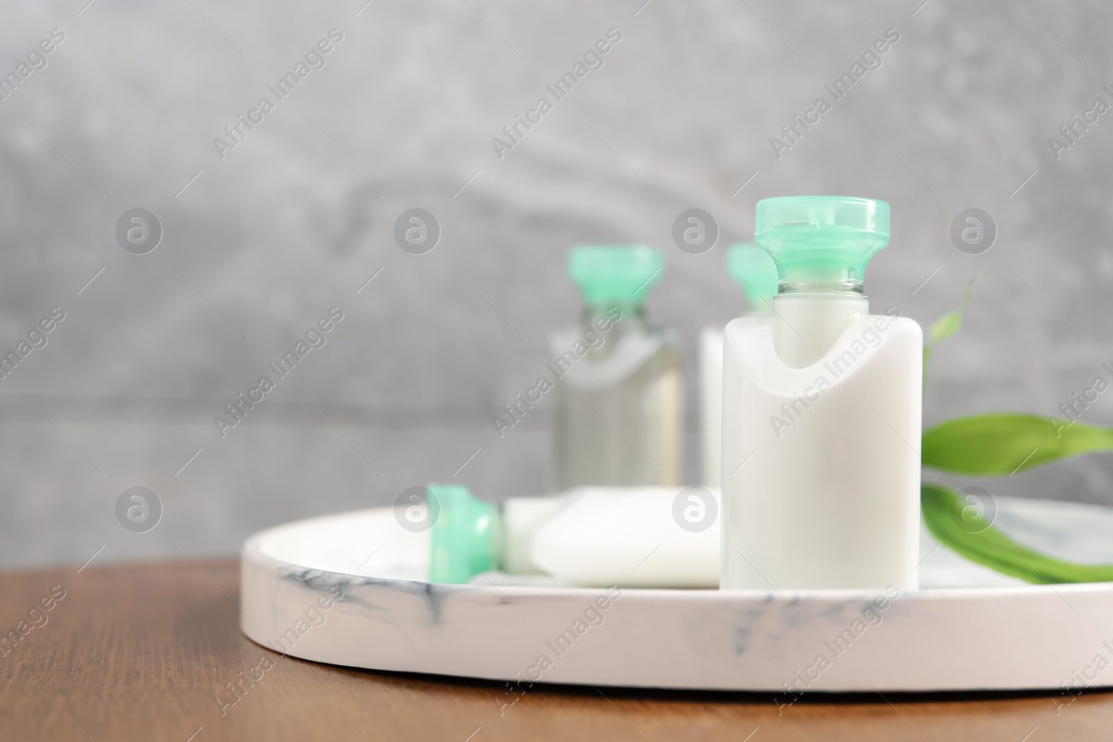 Photo of Mini bottles of cosmetic products on wooden table, closeup. Space for text