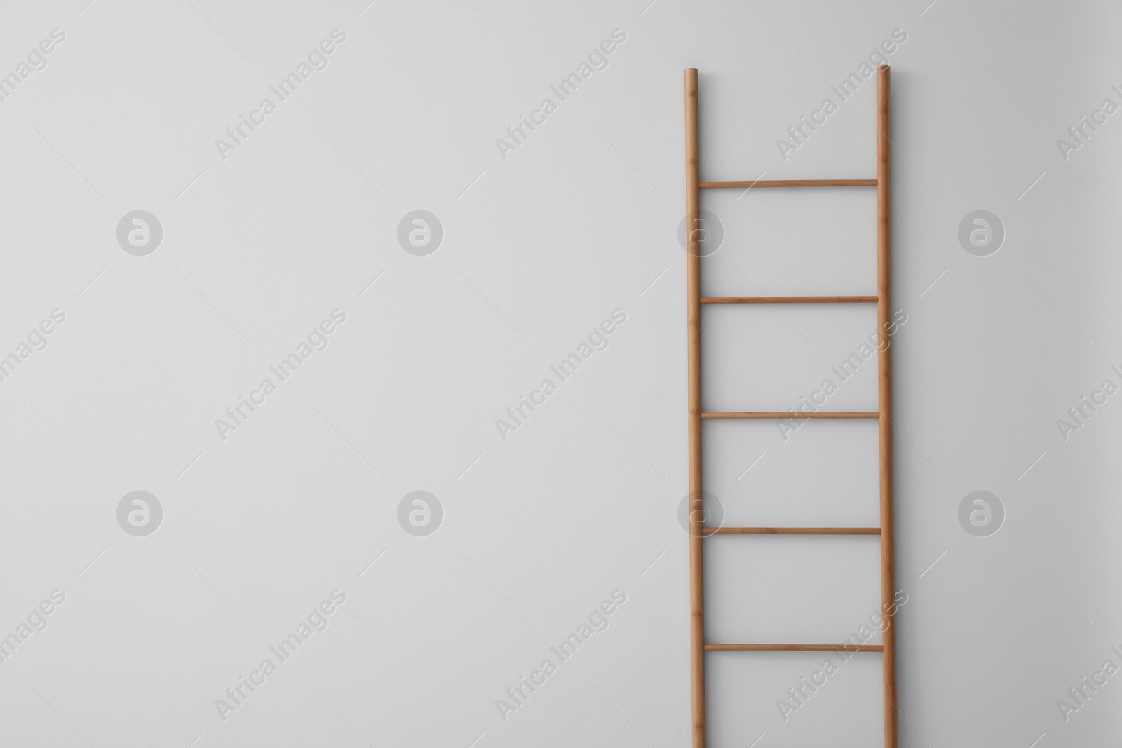 Photo of Modern wooden ladder on white background. Space for text