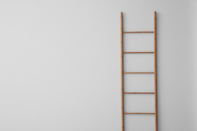 Photo of Modern wooden ladder on white background. Space for text