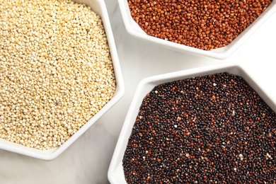 Bowls with different types of quinoa on board, top view