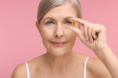 Photo of Beautiful woman with vitamin capsule on pink background