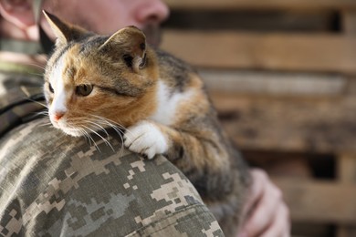 Photo of Ukrainian soldier with little stray cat outdoors, closeup. Space for text