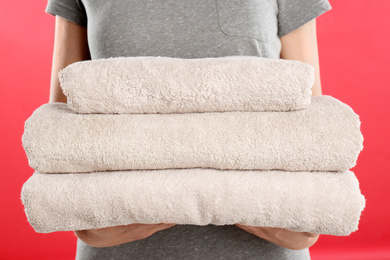 Photo of Woman holding fresh towels on red background, closeup