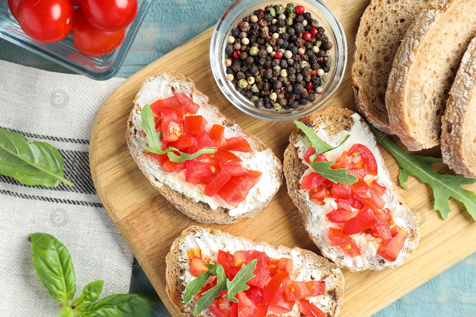 Photo of Wooden board with delicious tomato bruschettas on table, flat lay