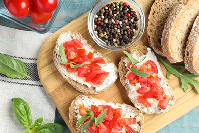 Photo of Wooden board with delicious tomato bruschettas on table, flat lay