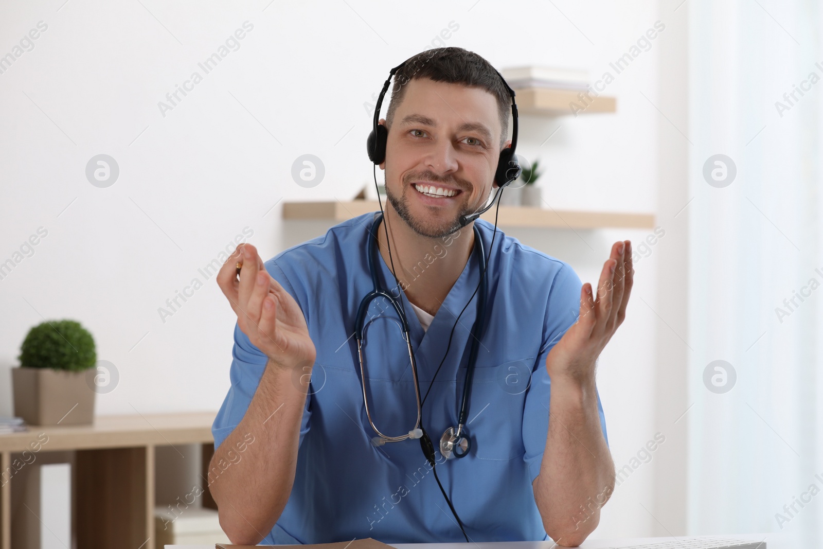 Photo of Doctor with headset sitting at desk in clinic. Health service hotline