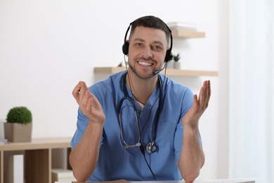 Doctor with headset sitting at desk in clinic. Health service hotline