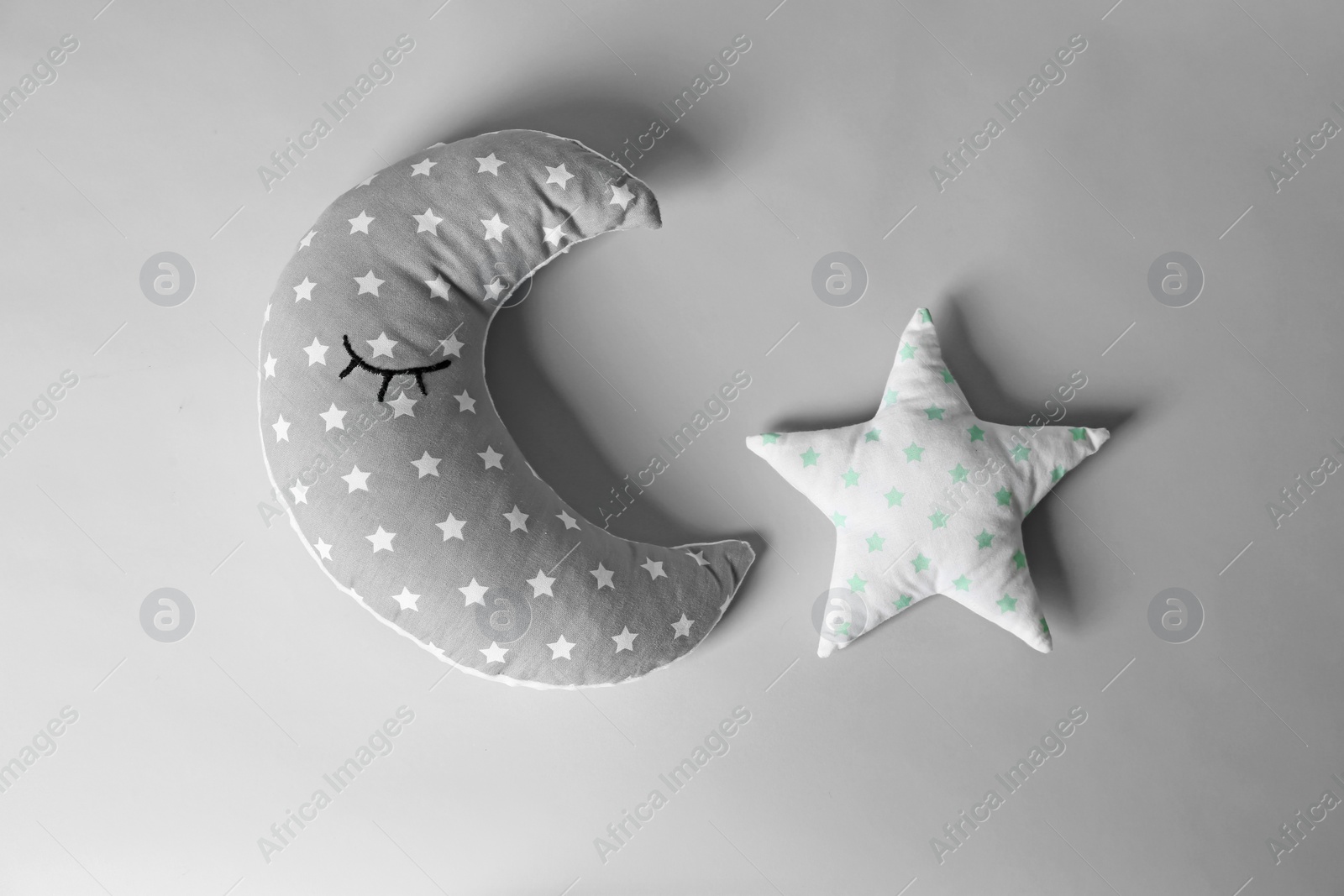 Photo of Soft decorative pillows in shape of moon and star on light background