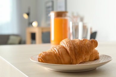 Plate with tasty fresh croissant on table