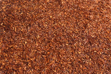 Heap of dry rooibos tea leaves as background, closeup