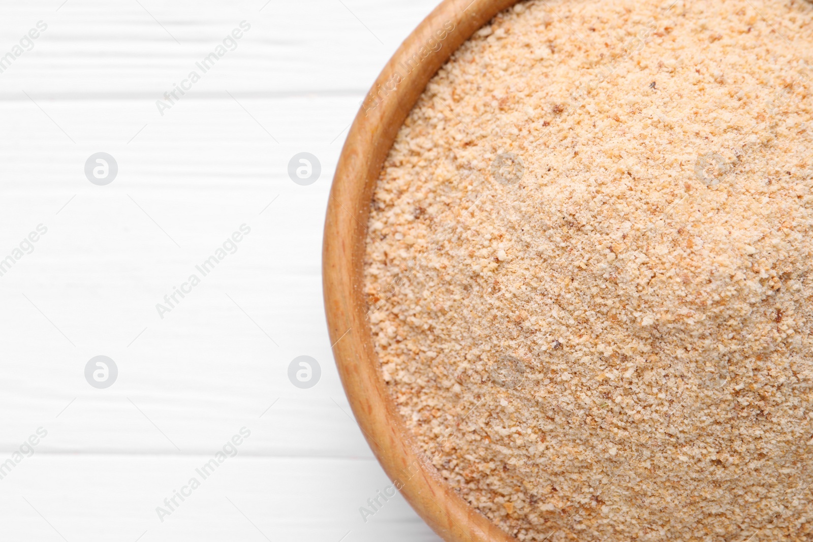 Photo of Fresh breadcrumbs in bowl on white wooden table, top view. Space for text