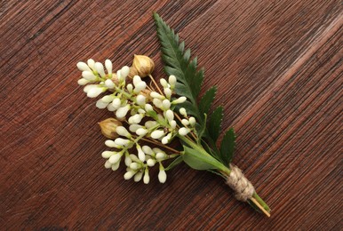 Photo of Small stylish boutonniere on wooden table, top view