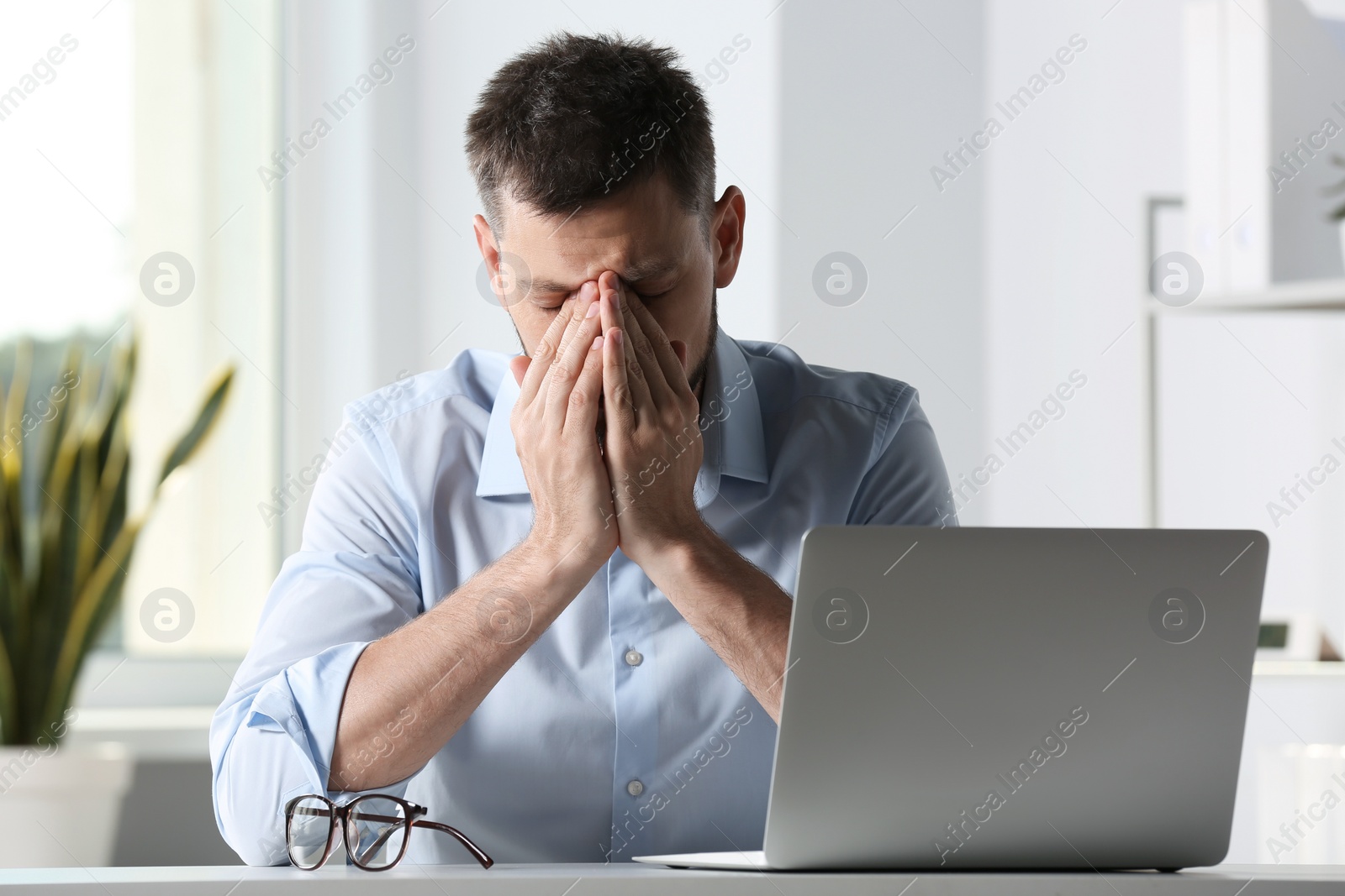 Photo of Man suffering from eyestrain at desk in office