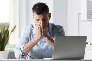 Man suffering from eyestrain at desk in office