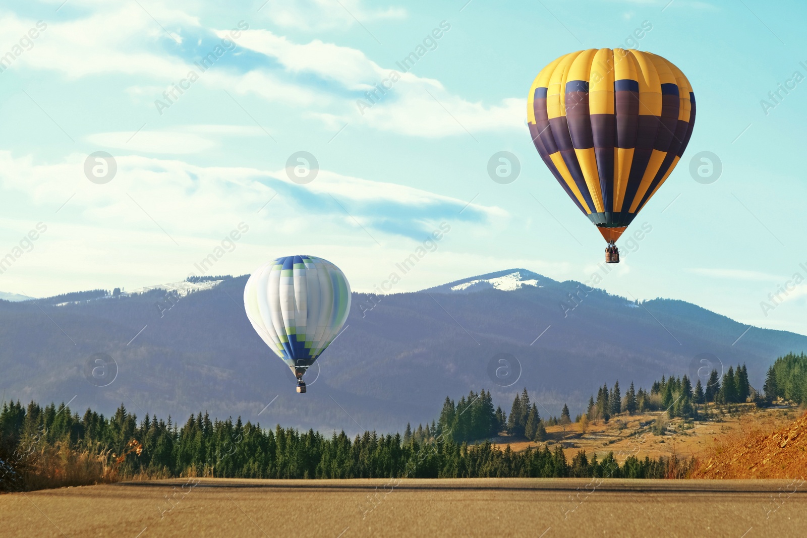 Photo of Hot air balloons flying near forest and mountains