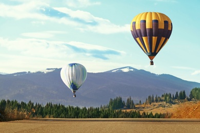 Hot air balloons flying near forest and mountains