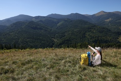 Tourist with hiking equipment and binoculars in mountains