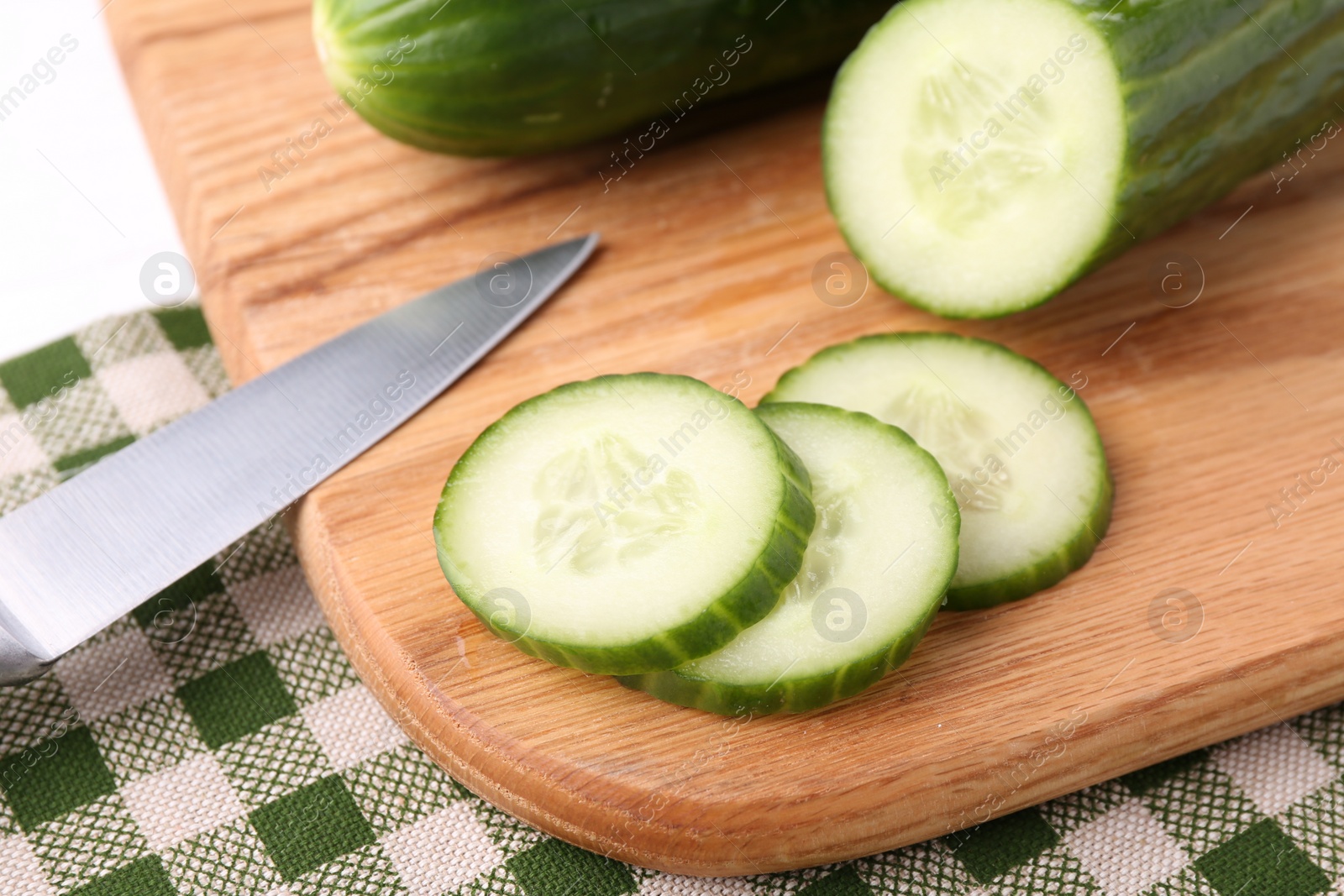 Photo of Cucumbers, knife and cutting board on table, closeup