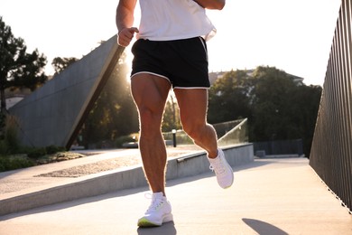 Man running outdoors on sunny day, closeup