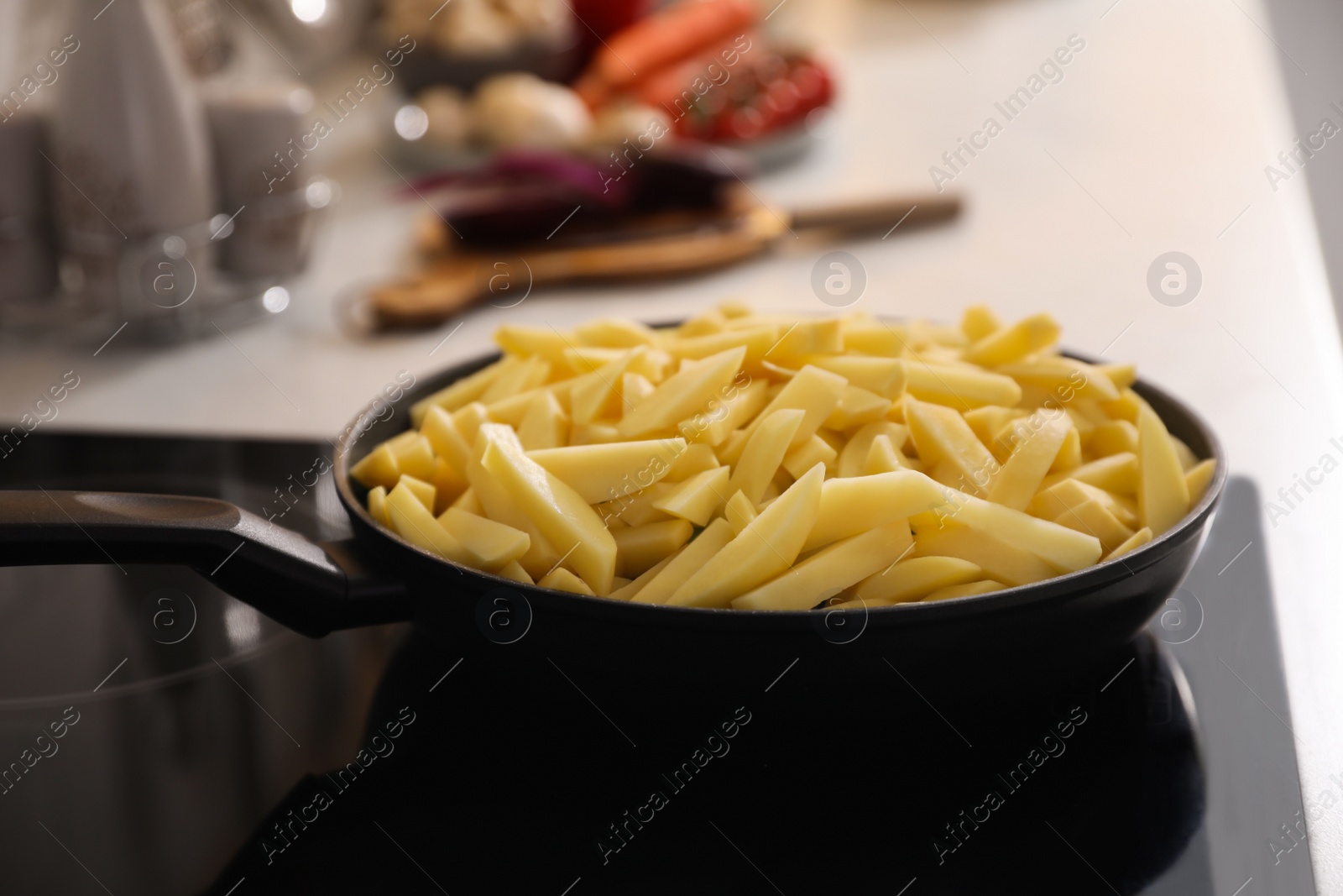 Photo of Frying pan with cut raw potatoes on cooktop