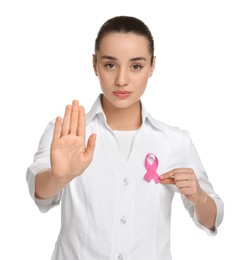 Photo of Mammologist with pink ribbon showing stop gesture on white background. Breast cancer awareness