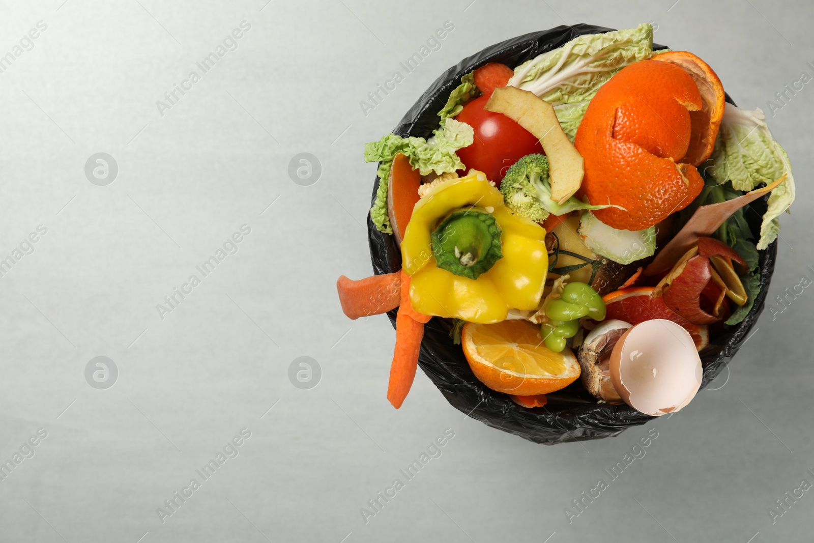 Photo of Natural garbage in trash bin on light background, top view with space for text. Composting of organic waste