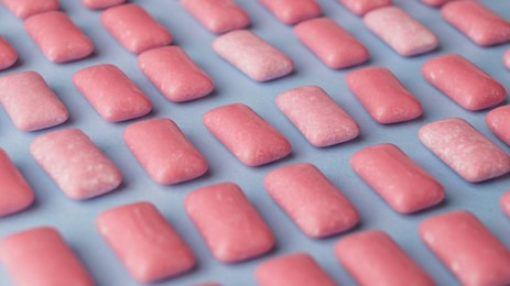 Photo of Many sweet chewing gums on light blue background, closeup