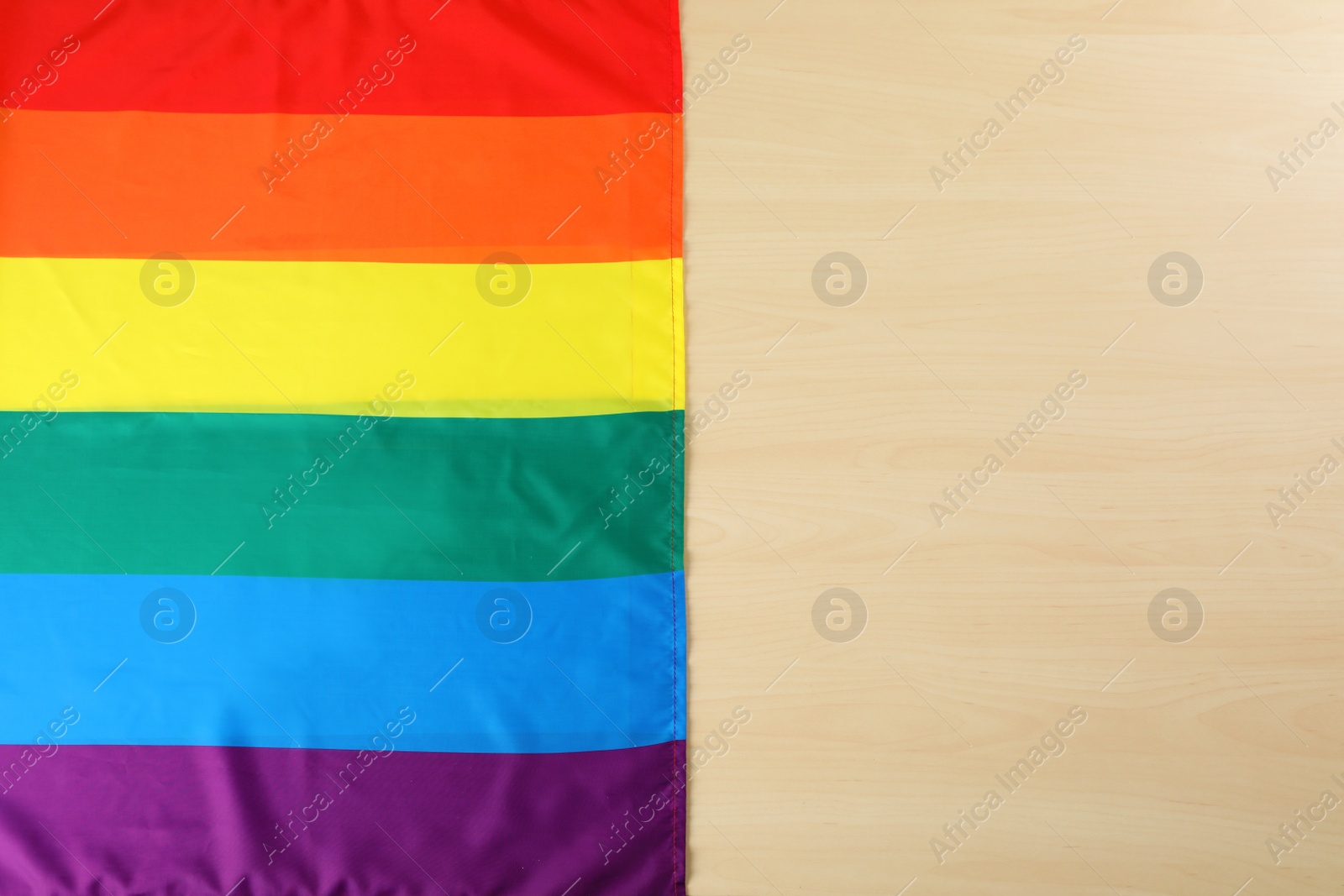 Photo of Rainbow gay flag on wooden background, top view with space for text. LGBT concept