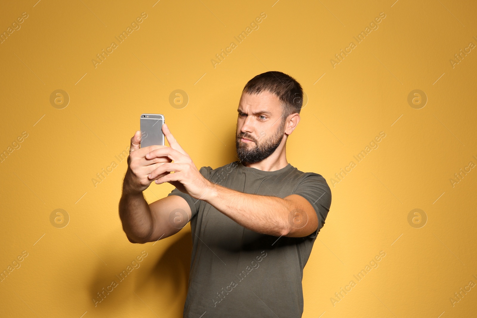 Photo of Man in casual clothes taking selfie on color background