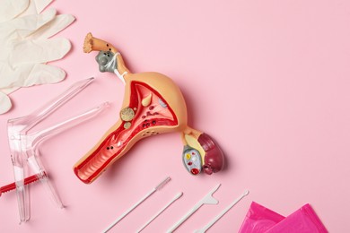 Photo of Gynecological examination kit and anatomical uterus model on pink background, flat lay. Space for text