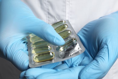 Doctor taking pill out from blister pack on grey background, closeup