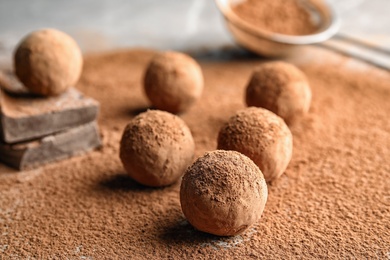 Photo of Sweet raw chocolate truffles powdered with cocoa on table