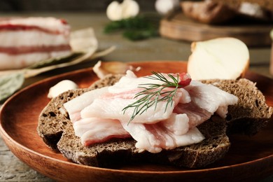 Tasty salt pork with rye bread and dill on table, closeup