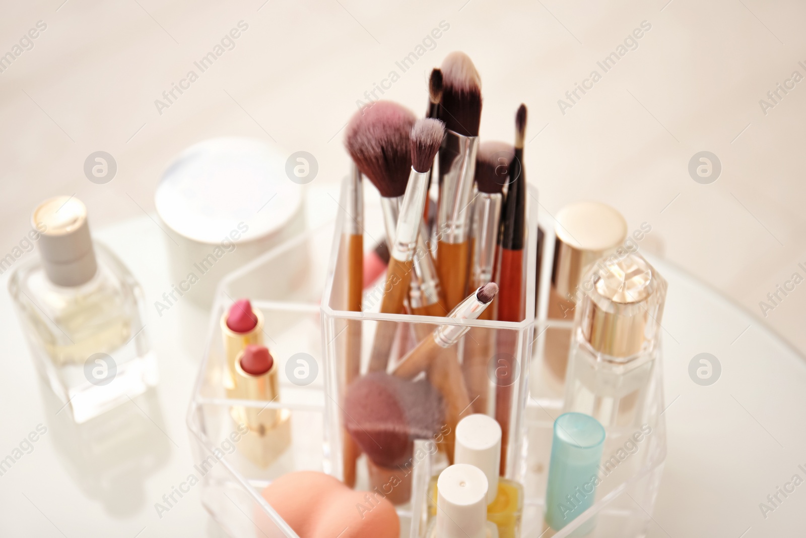 Photo of Makeup cosmetic products and tools in organizer on dressing table, closeup