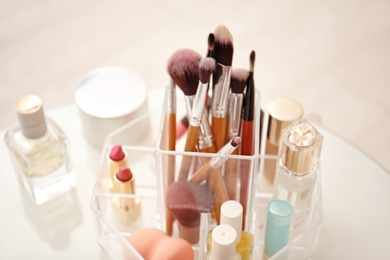 Makeup cosmetic products and tools in organizer on dressing table, closeup