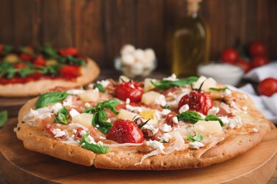 Photo of Pita pizza with prosciutto, pineapple, grilled tomatoes and egg on wooden tray, closeup