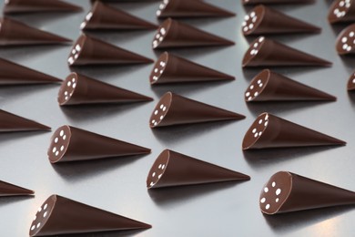 Photo of Many tasty chocolate candies on metal surface. Production line