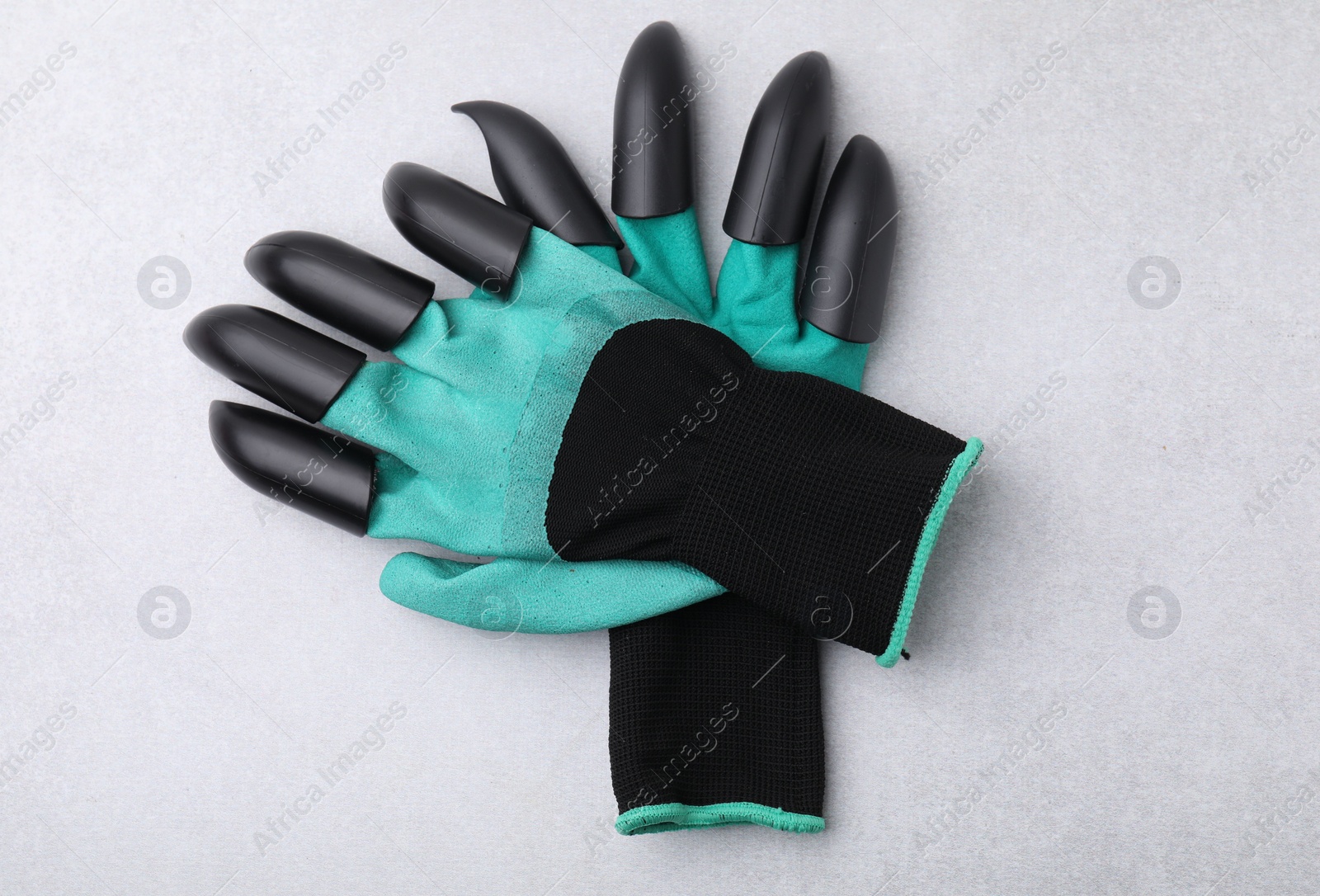 Photo of Pair of claw gardening gloves on light grey table, top view