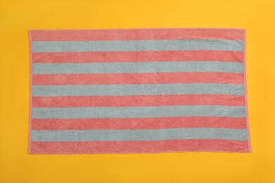 Photo of Striped beach towel on yellow background, top view