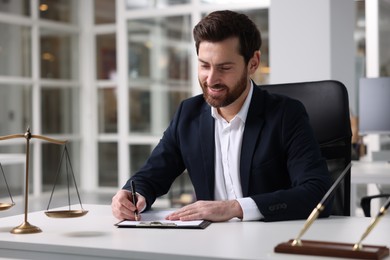 Photo of Smiling lawyer working at table in office