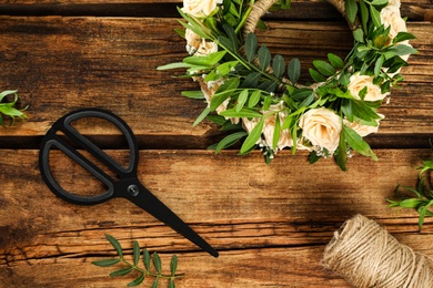 Photo of Flat lay composition with wreath made of beautiful flowers on wooden table