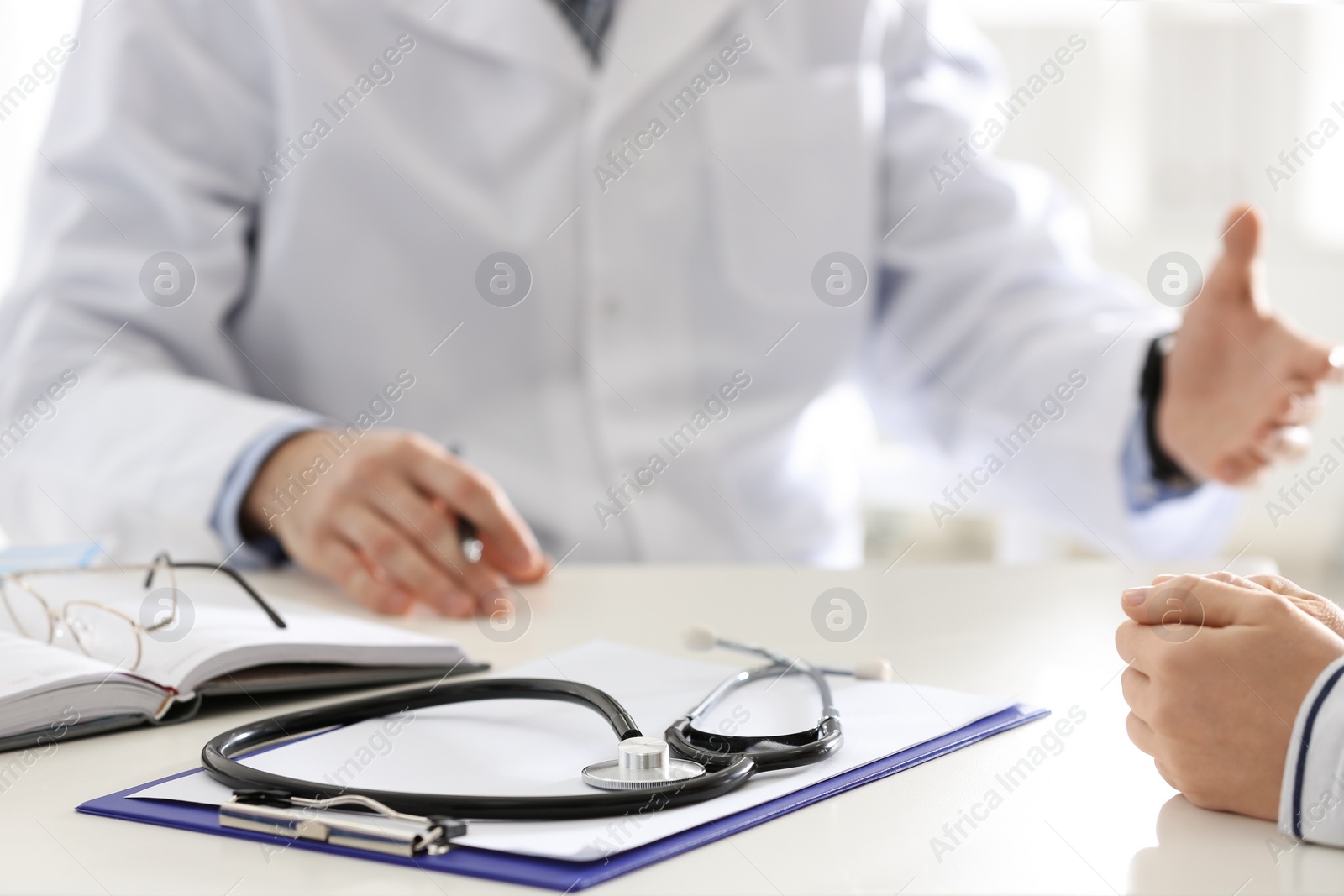 Photo of Doctor consulting patient at desk in clinic, closeup