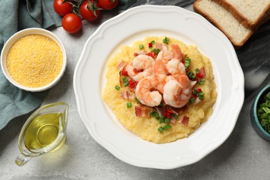 Photo of Plate with fresh tasty shrimps, bacon, grits, green onion and pepper on gray textured table, flat lay