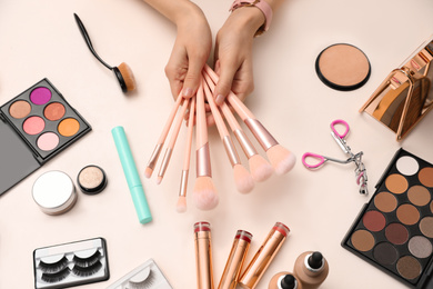 Beauty blogger with set of make up brushes at table, top view