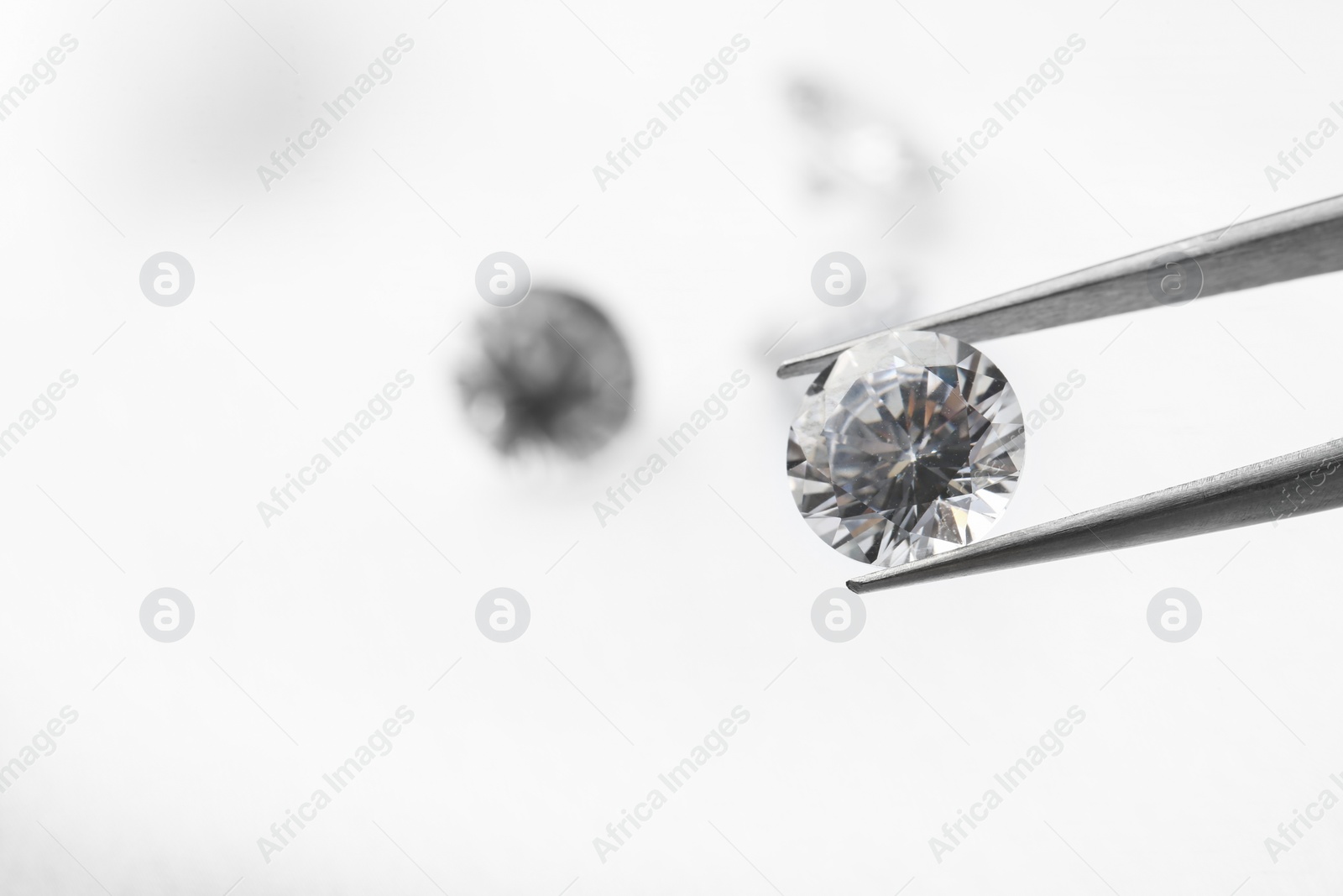 Photo of Tweezers with beautiful shiny diamond on light background, closeup. Space for text