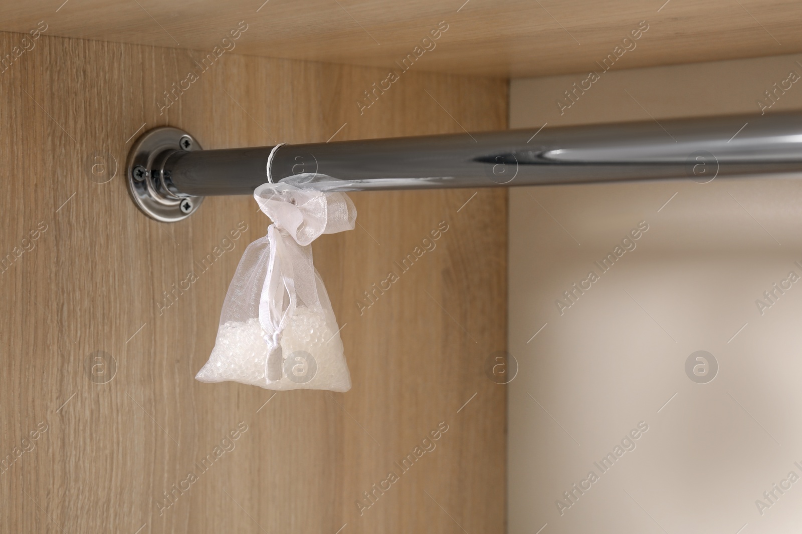 Photo of Scented sachet hanging on metal bar in wardrobe