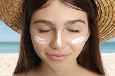 Image of Teenage girl with sun protection cream on her face near sea, closeup